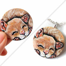 Load image into Gallery viewer, a smooth wood circle, hand painted with a sleeping hamster. available as a keepsake or pendant necklace
