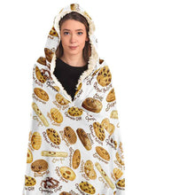 Load image into Gallery viewer, a woman wearing the Happy Cookies Hooded Blanket, featuring 10 illustrated smiling cookies patterned all over, lined with sherpa
