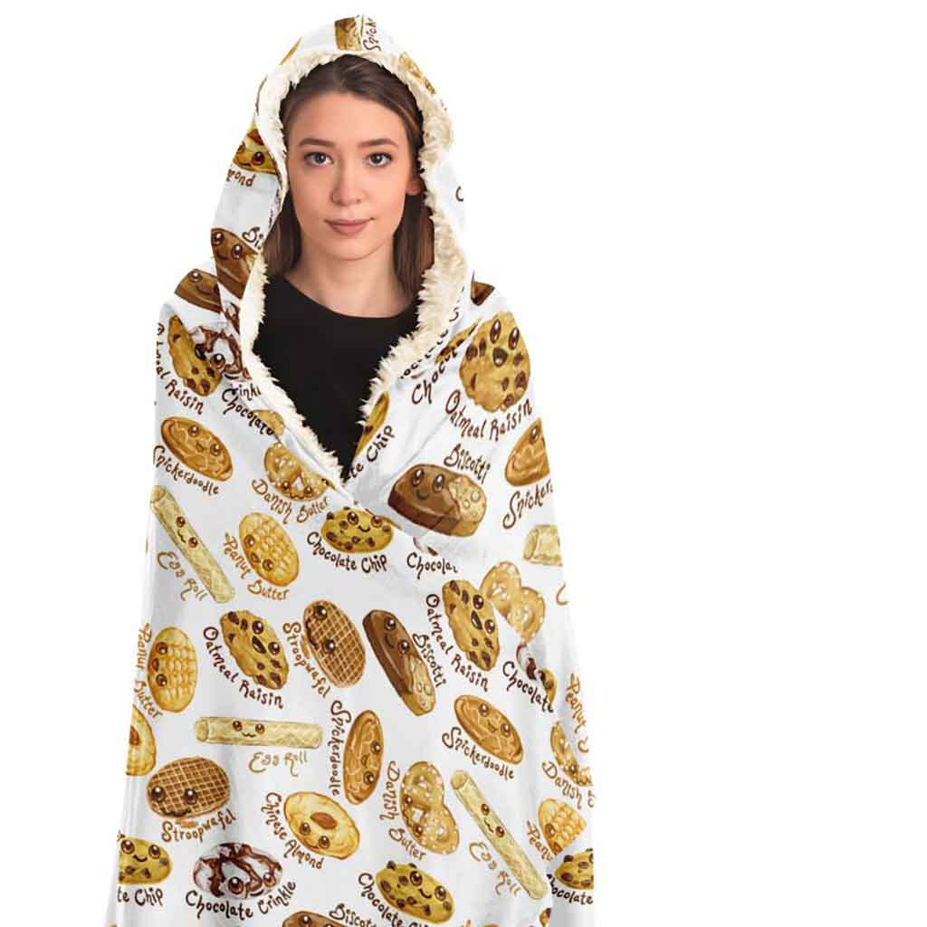 a woman wearing the Happy Cookies Hooded Blanket, featuring 10 illustrated smiling cookies patterned all over, lined with sherpa