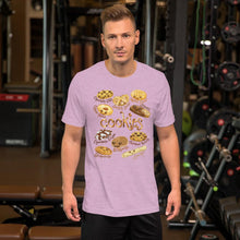 Load image into Gallery viewer, A man wearing the Happy Cookies Premium Unisex T-Shirt in the colour heather prism lilac, featuring an illustration of ten different types of cookies with smiling faces
