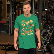 Load image into Gallery viewer, A man wearing the Happy Cookies Premium Unisex T-Shirt in the colour kelly green, featuring art of ten different types of cookies with smiling faces
