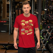 Load image into Gallery viewer, A man wearing the Happy Cookies Premium Unisex T-Shirt in the colour red, featuring a graphic of ten different types of cookies with smiling faces
