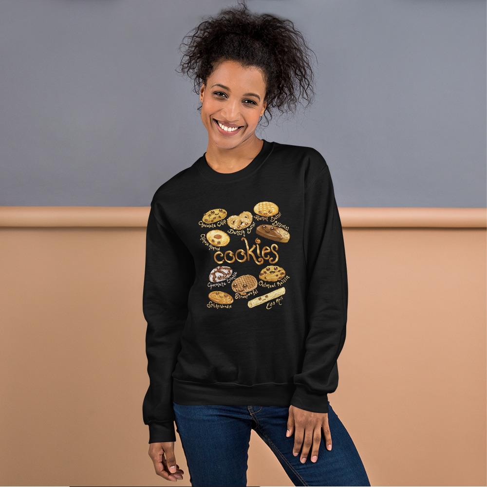 A woman is wearing the Happy Cookies Unisex Sweatshirt in the colour black, which features a graphic of 10 different types of cookies with smiley faces