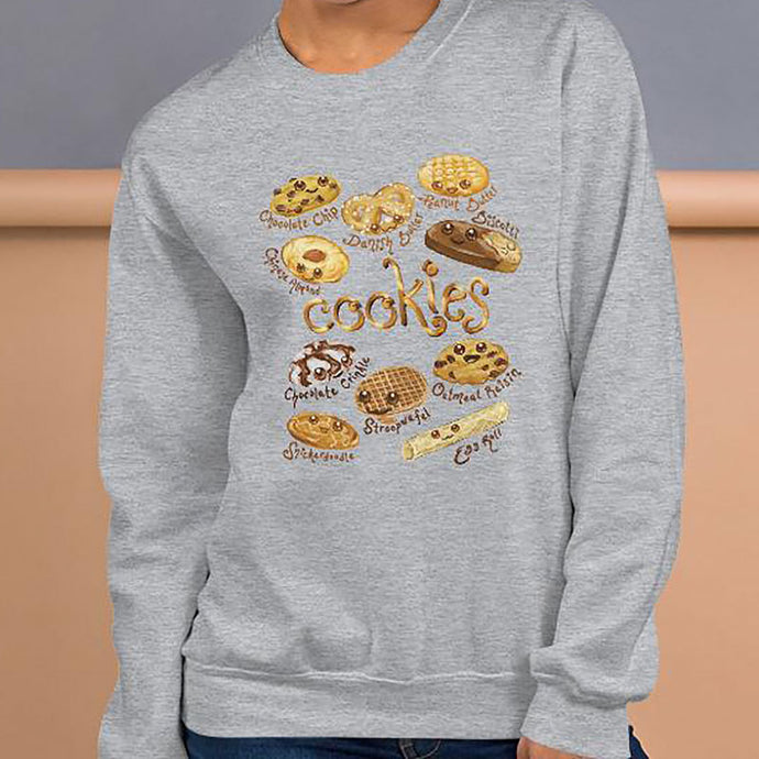 A woman is wearing the Happy Cookies Unisex Sweatshirt in the colour sport grey, which features an illustration of 10 different kinds of cookies with smiley faces