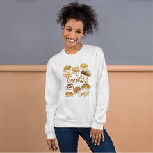 Load image into Gallery viewer, A woman is wearing the Happy Cookies Unisex Sweatshirt in the colour white, which features an illustration of 10 different types of cookies with smiley faces
