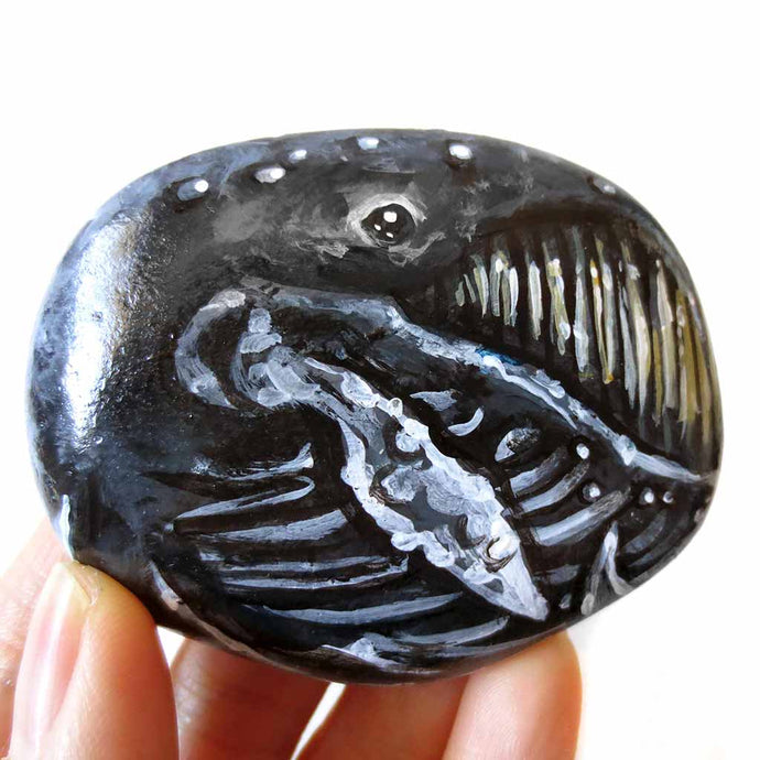 portrait of a humpback whale, hand painted on a flat, round rock
