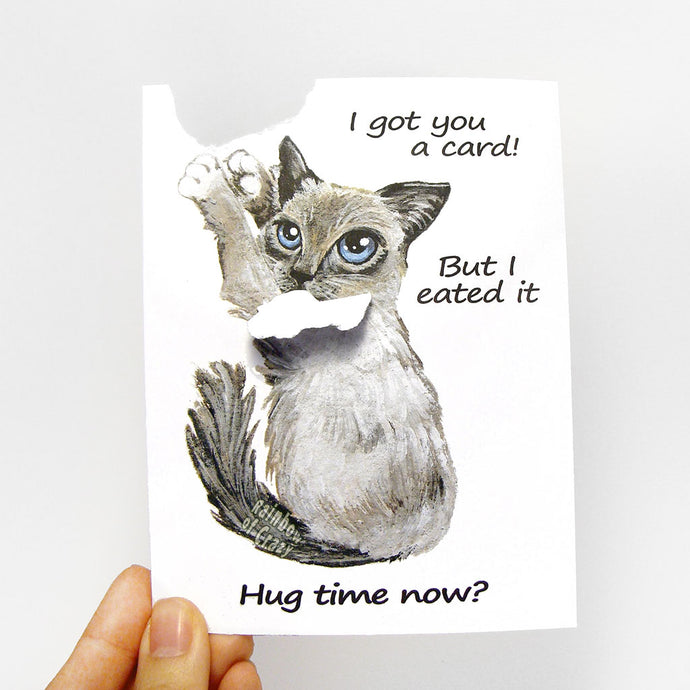 A greeting card featuring art of a birman cat. A piece of the greeting card has been ripped off and is attached to the cat's mouth. Card reads, 