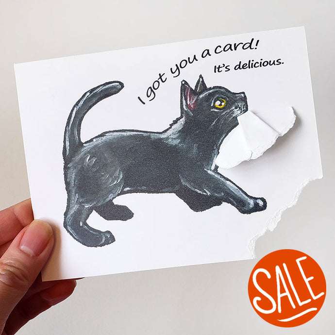 a greeting card with art of a black cat, ripping a corner of the card out with its mouth. the card reads, 