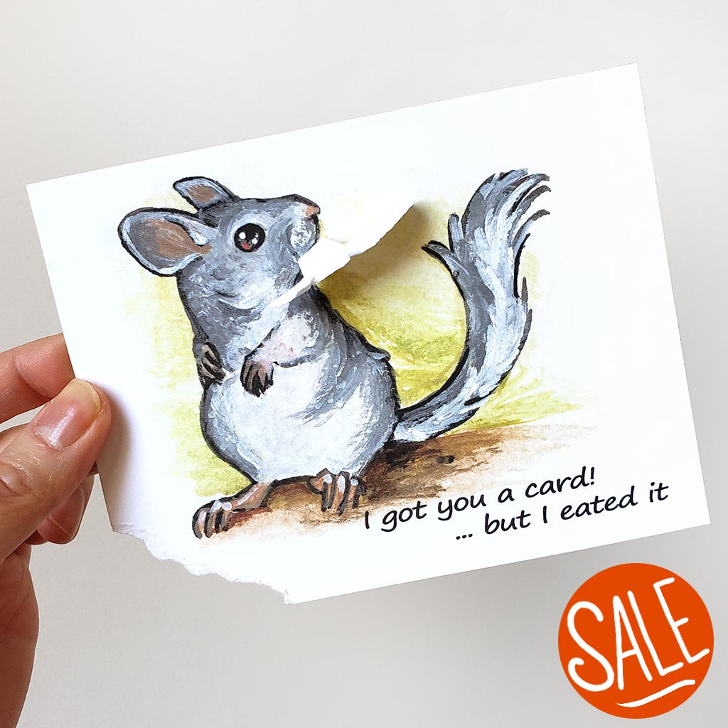 a greeting card with artwork of a chinchilla, holding a ripped piece of the bottom corner of the card. The card reads, 