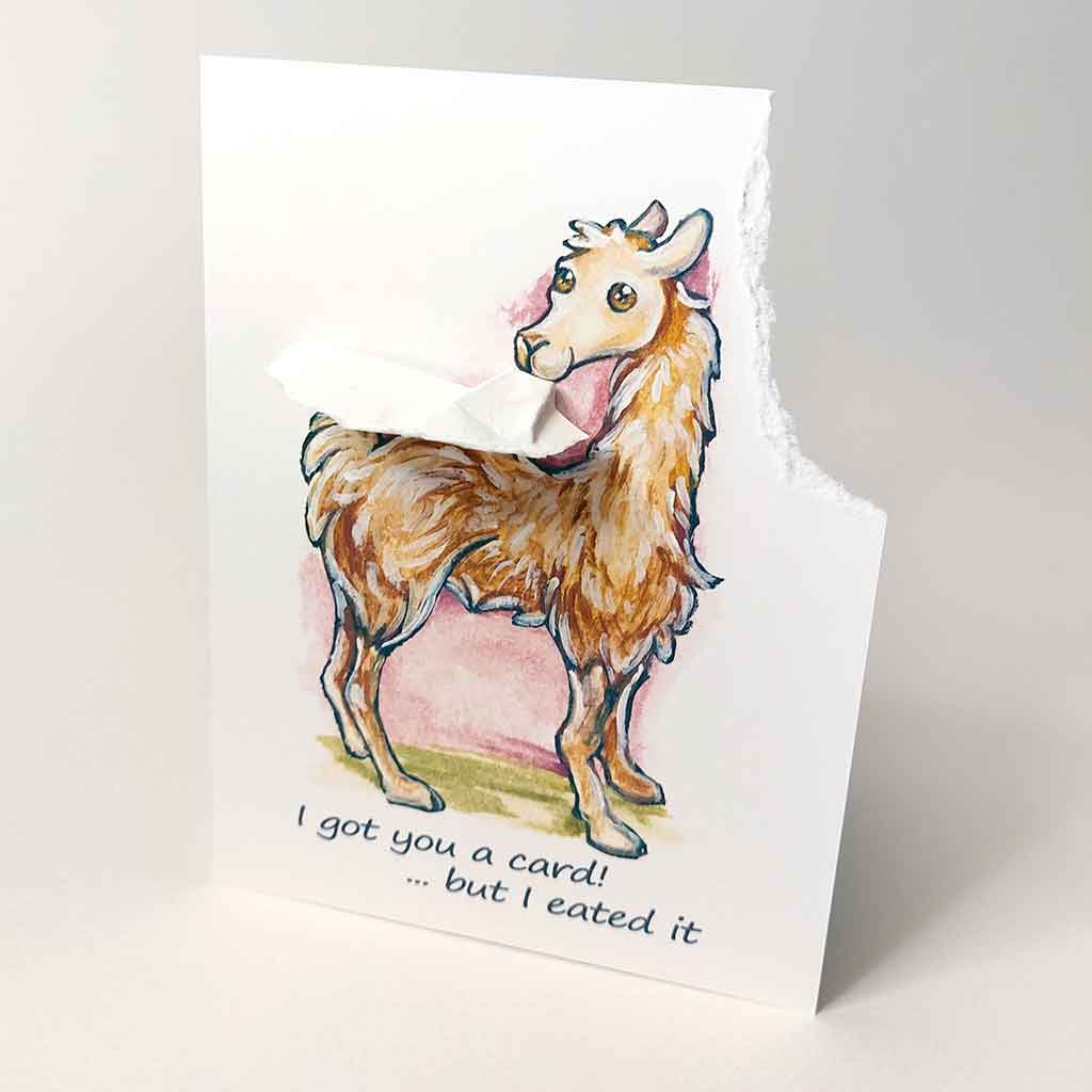 a greeting card featuring an illustration of a smiling llama. the top right corner has been torn off and hangs from the llama's mouth. the card reads, 