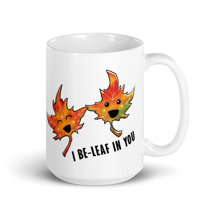 An 15 oz white ceramic mug, printed with art of two maple leaves, and the words. 