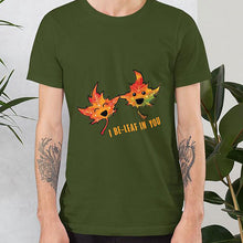 Load image into Gallery viewer, A man wearing the I Believe in You Leaf Premium Unisex T-Shirt in the colour olive green, which includes art of two maple leaves and the words, &quot;I be-leaf in you&quot;
