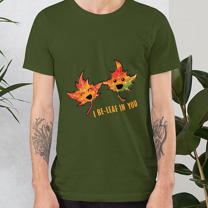 A man wearing the I Believe in You Leaf Premium Unisex T-Shirt in the colour olive green, which includes art of two maple leaves and the words, 
