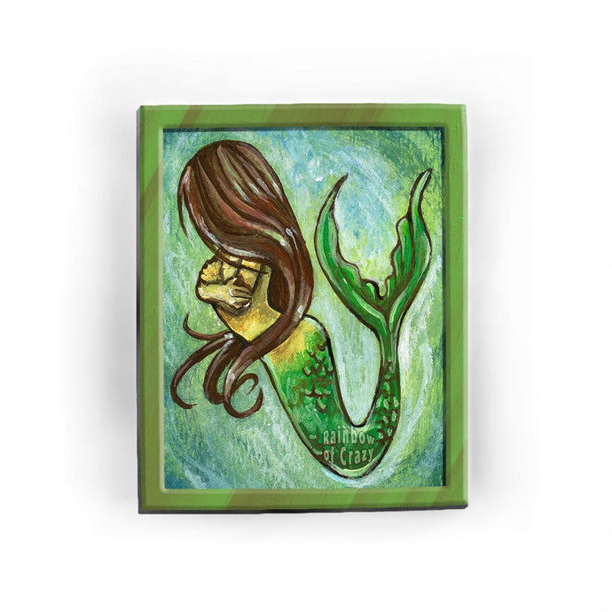 An art print featuring an illustration of a mermaid with her face hidden behind long, brown hair. 