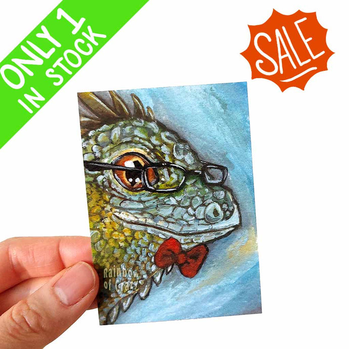 an aceo featuring art of an iguana, wearing glasses and a red bow tie
