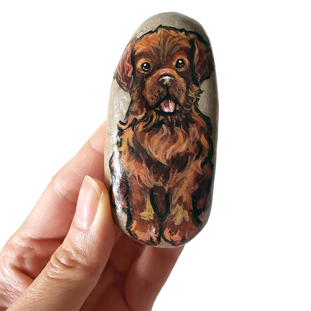 a beach stone painted with a brown Newfoundland dog