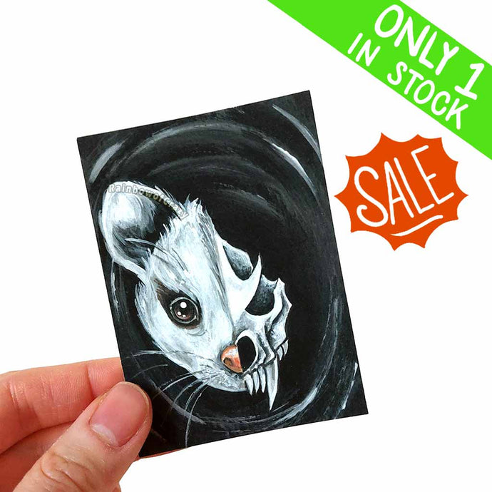 an aceo that features a split image of a cute possum on one side, and its slightly scary, stylized skull on the other.