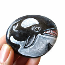 Load image into Gallery viewer, a round, flat beach stone is hand painted with art of an orca whale
