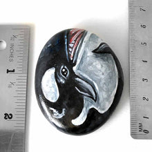 Load image into Gallery viewer, a round, flat beach stone is hand painted with art of an orca whale
