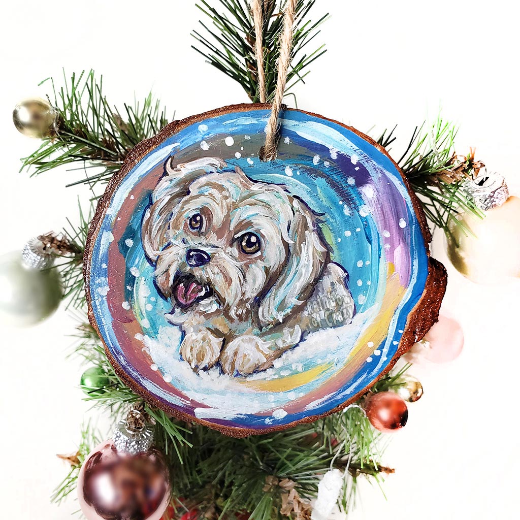 A wood ornament with a portrait of a white Havanese dog in front of a snowy background