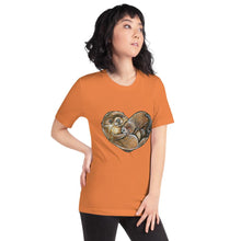 Load image into Gallery viewer, A woman wearing the Otters Love Premium Unisex T-Shirt in the colour burnt orange, which includes an image  of two otters forming the shape of a heart.

