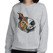 Load image into Gallery viewer, A woman wears a unisex sweatshirt in the colour sport grey, printed with artwork of a split image: the left side features an owl&#39;s face, and the right side features an evil looking owl skull.
