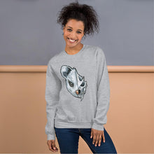 Load image into Gallery viewer, A woman wears a unisex sweatshirt in the colour sport grey, printed with a graphic of a split image: the left side features a possum&#39;s face, and the right side features an evil looking possum skull.

