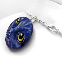 Load image into Gallery viewer, A wood pendant necklace, painted with the portrait of a cat in dark purple and black
