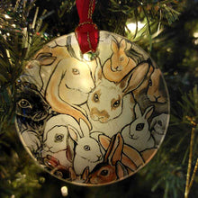 Load image into Gallery viewer, a round glass ornament, printed with a collage of different rabbit breeds, hanging from a Christmas tree with a red ribbon and gold string
