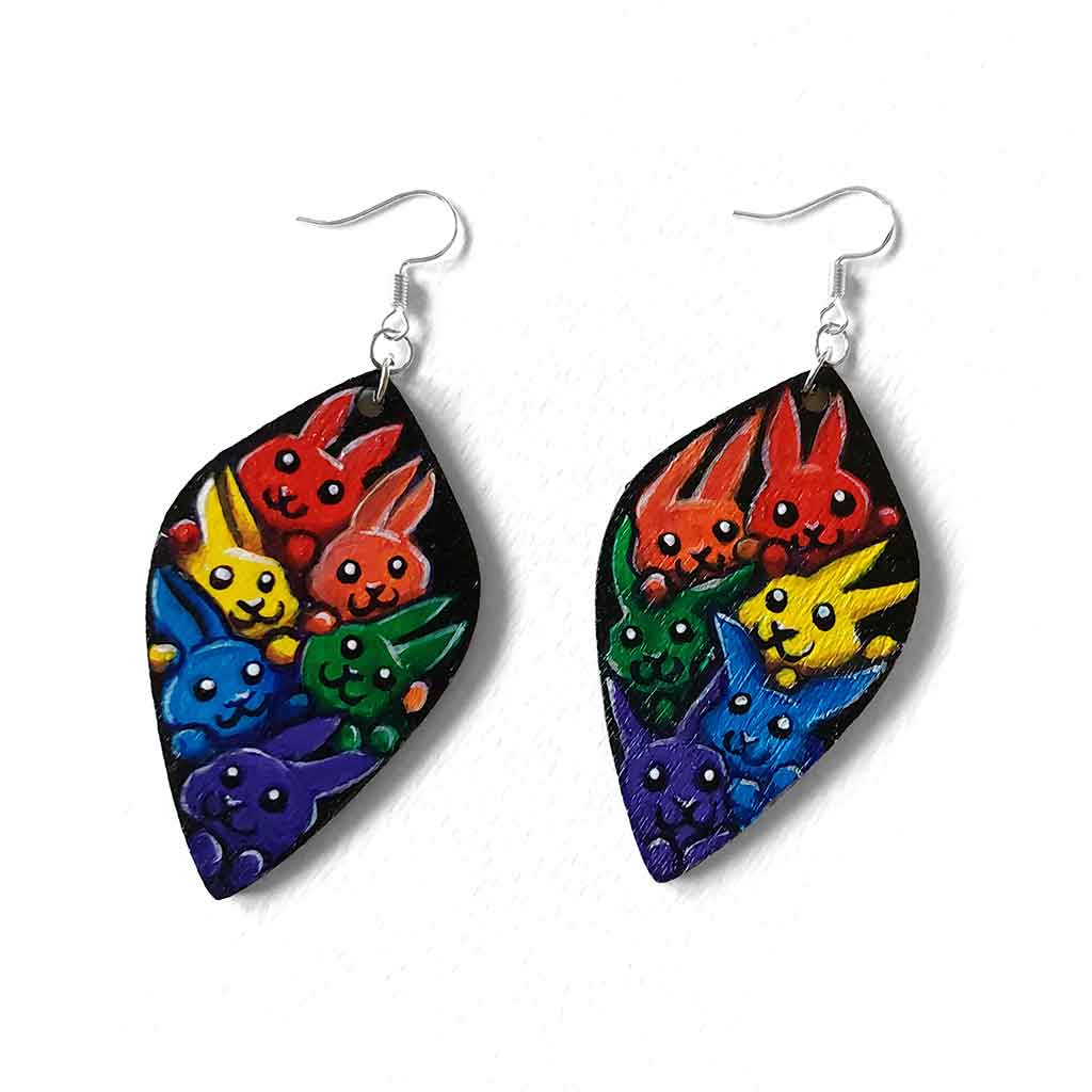 large leaf shaped wood earrings, hand painted with 6 rabbits in each colour of the rainbow, against a black background
