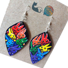 Load image into Gallery viewer, large leaf shaped wood earrings, hand painted with 6 rabbits in each colour of the rainbow, against a black background
