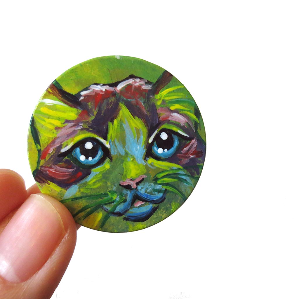 A wood pendant painted with the face of a Ragdoll cat. Available as a wood keepsake or necklace.