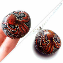 Load image into Gallery viewer, a small beach stone hand painted with art of a red octopus, available as a keepsake rock art, or as a pendant necklace
