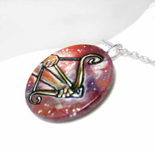 Load image into Gallery viewer, a wood circle pendant, hand painted, depicting the zodiac sign sagittarius: two hands hold a bow, with an arrow, ready to fire
