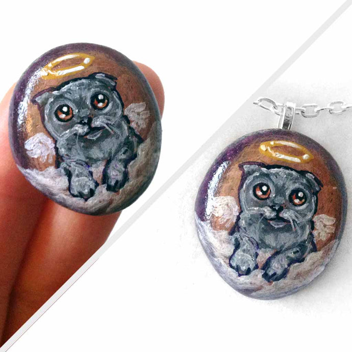 small beach stone, hand painted with a grey scottish fold cat as an angel in the clouds, available as a rock art keepsake or pendant necklace