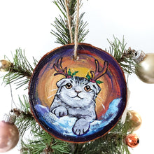 Load image into Gallery viewer, A wood Christmas ornament, hand painted with a portrait of a Scottish fold cat with reindeer antlers, sitting on the snow.

