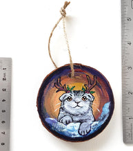 Load image into Gallery viewer, A wood Christmas ornament, hand painted with a portrait of a Scottish fold cat with reindeer antlers, sitting on the snow.

