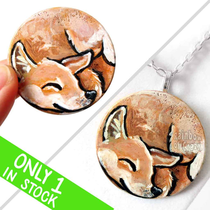 A circle wood disc painted with a portrait of a Shiba Inu dog having a nap, available as a keepsake or necklace