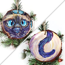 Load image into Gallery viewer, A wood ornament featuring art of a siamese cat&#39;s face with blue eyes, and it&#39;s tail on the back.
