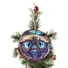Load image into Gallery viewer, A hand painted wood ornament with artwork of the face of a blue eyed siamese cat
