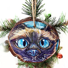 Load image into Gallery viewer, A wood ornament with a hand painted portrait of a siamese cat with blue eyes
