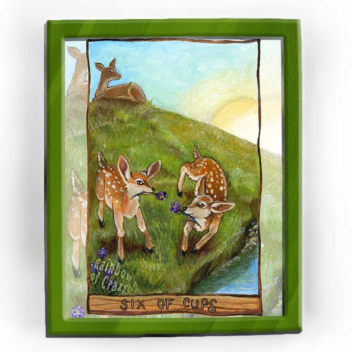 an art print of the six of cups tarot card from the animism tarot. two baby deer play in with crocus flowers in a field, with their mother watching over them in the distance.