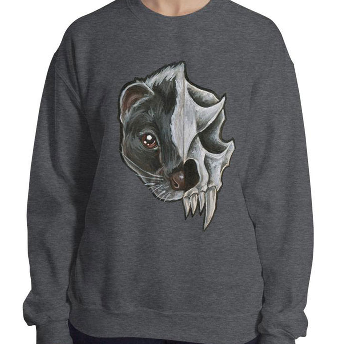 A woman wears a unisex sweatshirt in the colour dark heather grey, printed with a graphic of a split portrait: the left side features the face of a skunk, and the right side features an evil looking skunk skull