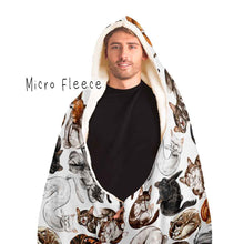 Load image into Gallery viewer, a man wears the Sleepy Cats Hooded Blanket, featuring illustrations of different sleeping cats, lined with micro fleece
