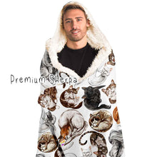 Load image into Gallery viewer, a man wears the Sleepy Cats Hooded Blanket, featuring illustrations of different sleeping cats, lined with premium sherpa
