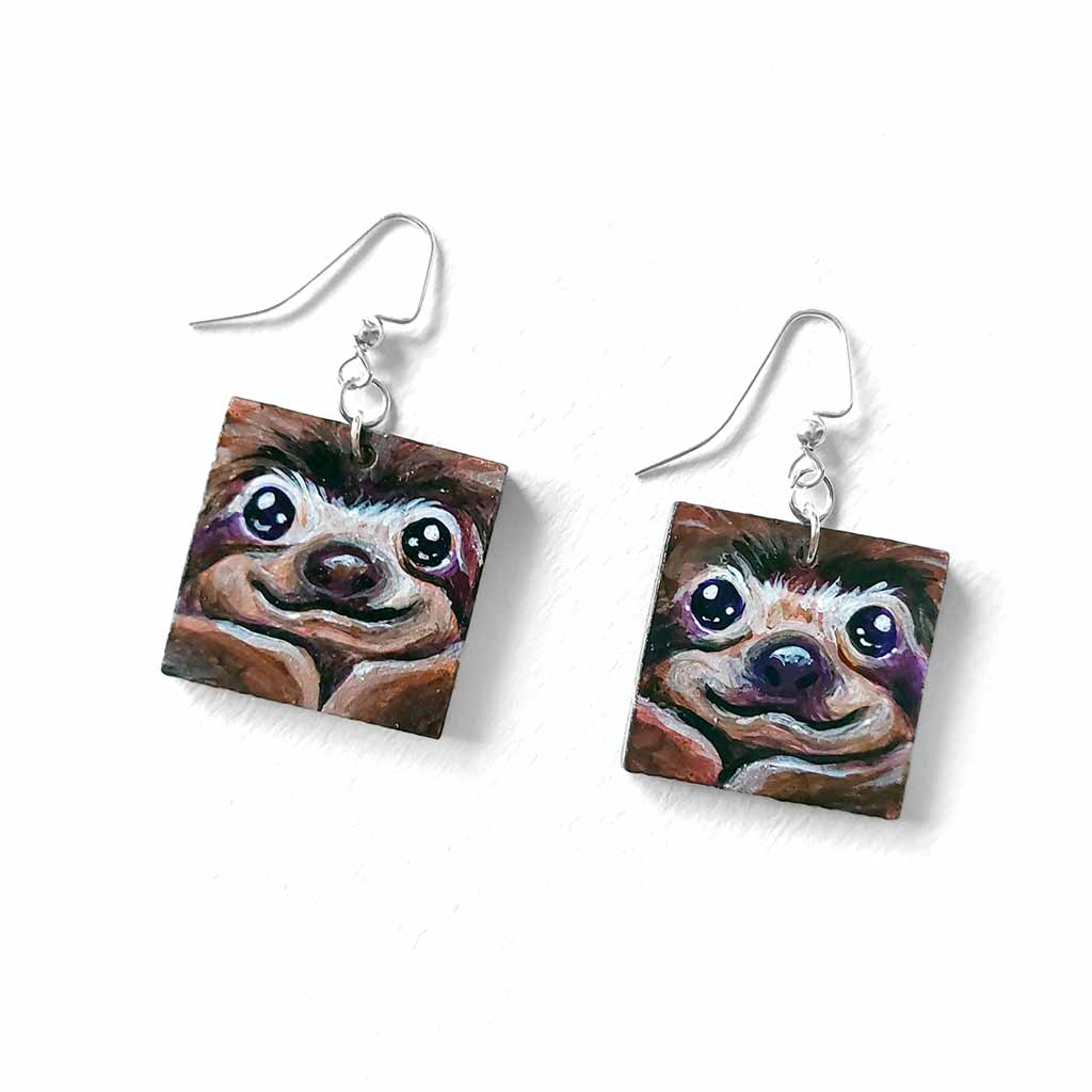 square wood fish hook earrings, hand painted with smiling sloth faces