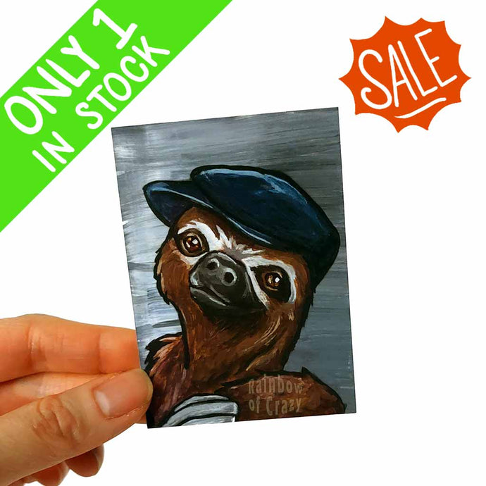 an aceo art print, featuring the portrait of a sloth, wearing a navy blue flat cap 