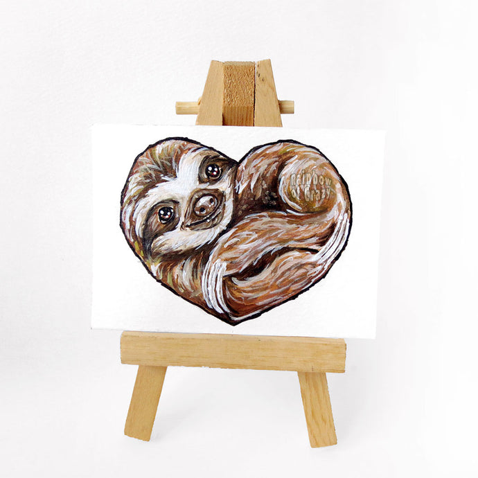 An ACEO sized painting of a sloth, curled up in the shape of a heart. 