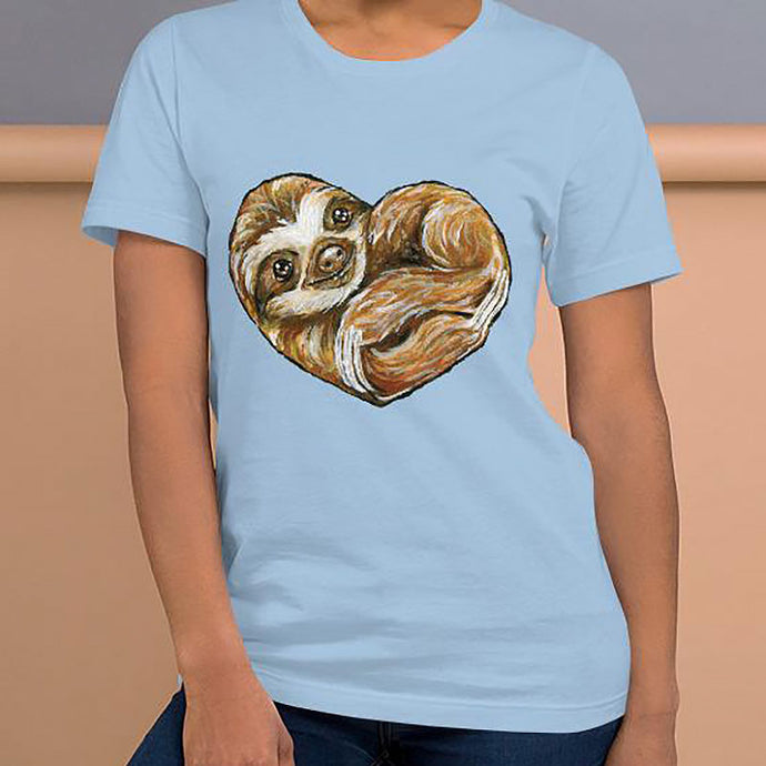 A woman is wearing the Sloth Love Unisex Premium T-Shirt in the colour light blue, which includes art of a sloth forming the shape of a heart.
