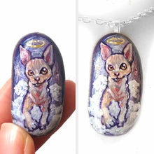 Load image into Gallery viewer, a beach stone, hand painted with a portrait of a sphynx cat as an angel in the clouds. available as a keepsake rock art, or pendnat necklace
